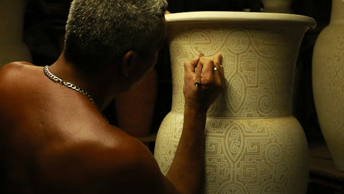 man painting a hand made pot