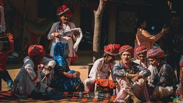 A group of people sitting in the ground in festive outfits.
