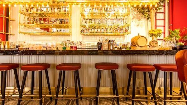 Brightly lit bar with high stools and a wide array of liquor bottles.