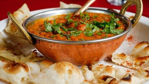 Image of curry with naan on the side of the plate