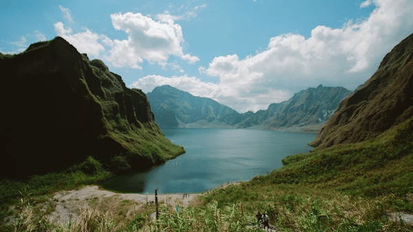 Scenic mountain lake with clear blue skies and rugged cliffs reflecting on the calm water.