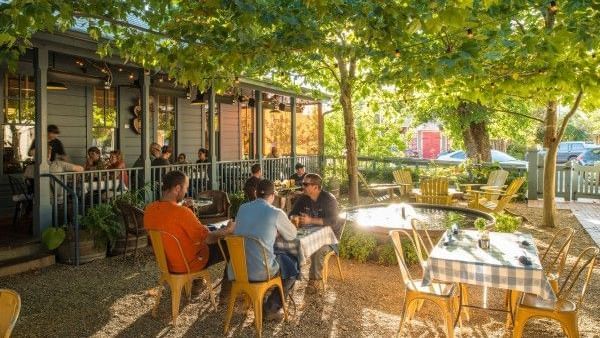 Guests relax and dine under the shade of trees on the inviting patio of the Tallman Hotel.