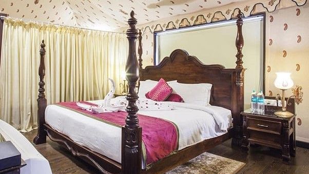 Side view of a room with a bed and a wooden side table beside the bed Rajasthali Resort & Spa Jaipur.
