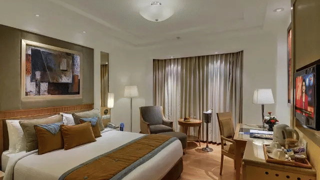 A room with polished wooden floors and a large bed at Eastlynn Collections Huda City Centre, Gurugram.