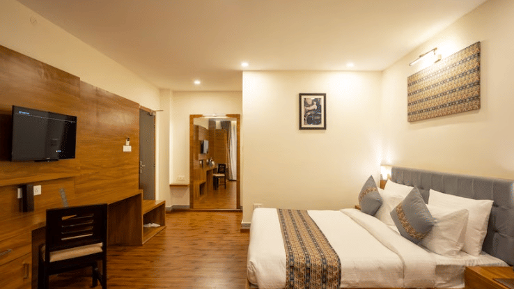 Deluxe Room at Voyage The Royal Retreat featuring a comfortable double bed, wooden interiors, and modern amenities.