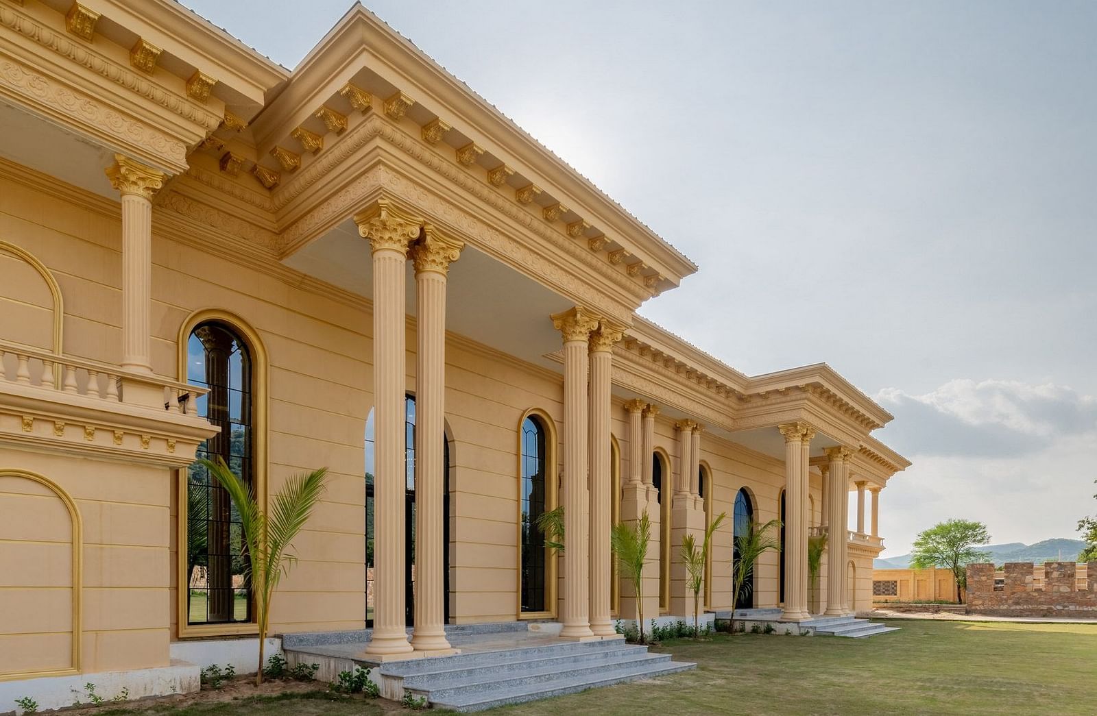 Side view of The Royal Know Banquet Hall’s facade at Valley by Grassfield, featuring grand entrance pillars and a clear sky in the background.
