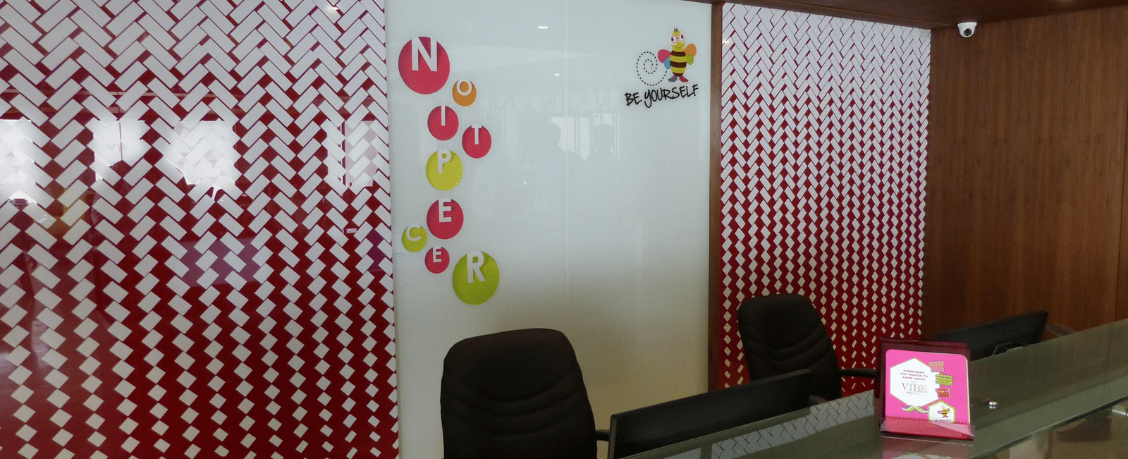 The reception area of Zibe Coimbatore by GRT Hotels featuring a desk with two chairs neatly arranged.