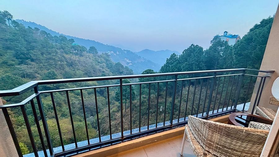 Balcony view with a chair overlooking lush green hills and a serene valley at ARNISA Boutique Hotel