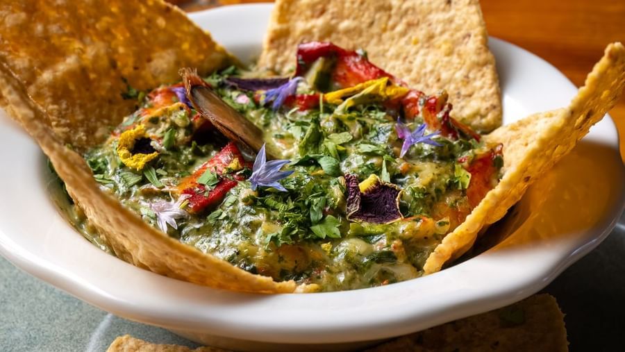 Guacamole served with tortilla chips in a bowl with fresh garnishes at Narrow Gauge Inn.