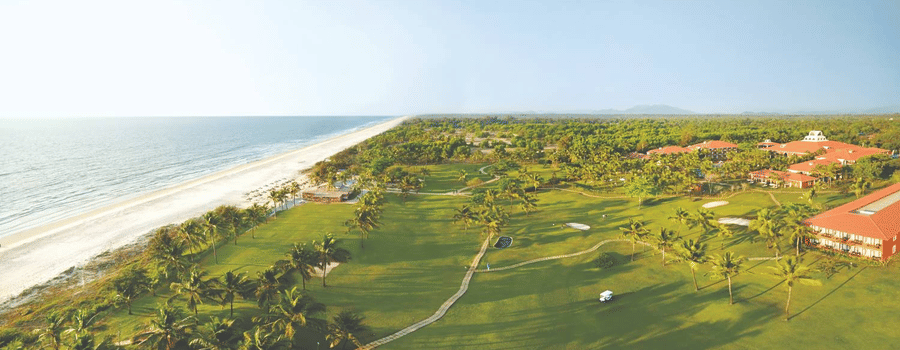 A scenic view of a lush golf course stretching along a pristine coastline, offering a serene and picturesque setting for golf enthusiasts.