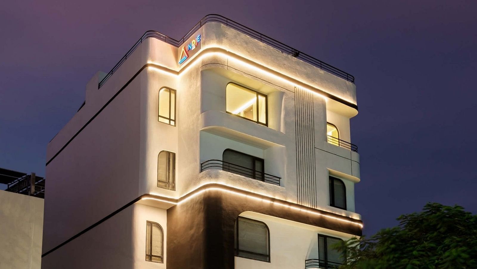The facade of Indie Stays, Jaipur, glows brightly under night lights against the dark sky.