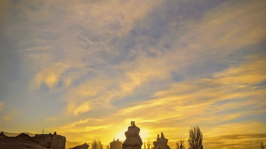Silhouette of traditional stone chortens against a dramatic sunset sky at Indus Serenity Retreat.