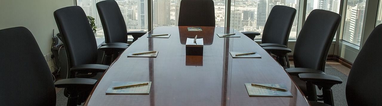 Board room with well arranged chair and notepad on the table.