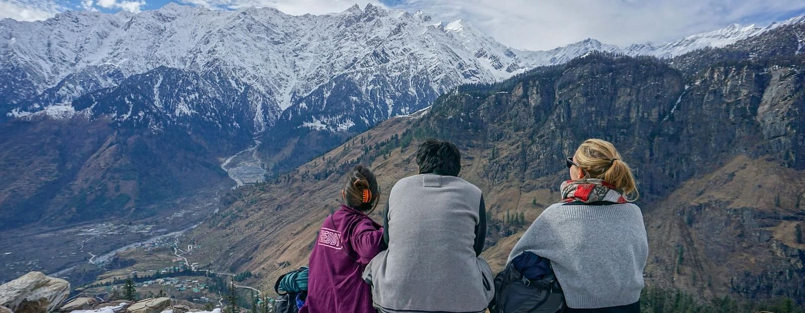 Three people are looking at the view of the mountain