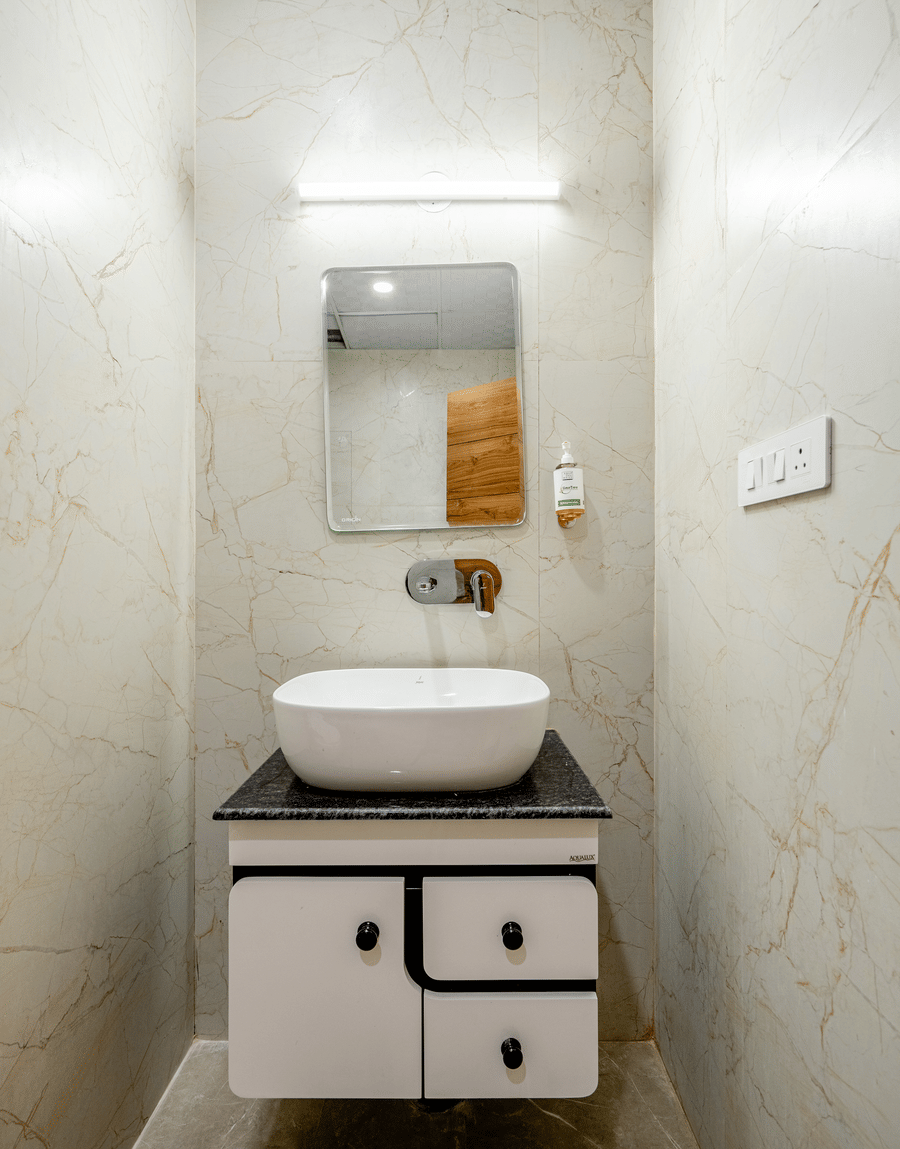Sleek counter-top ceramic washbasin sitting on a modern wooden vanity unit with a back lit mirror.
