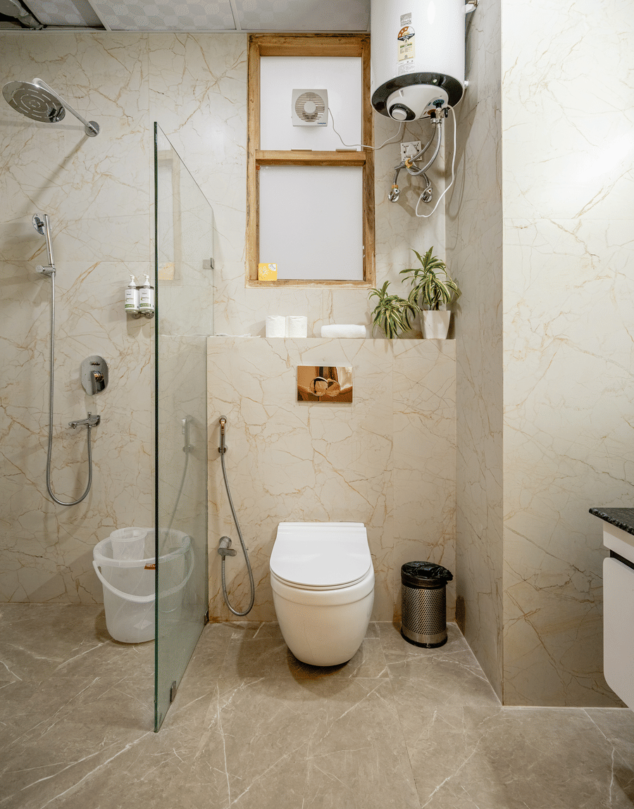 Modern hotel bathroom featuring a glass shower cubicle, wall-mounted toilet, and tiled floors.