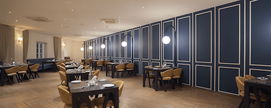 alt-text Full view shot of the restaurant at Pride Resort, Rajkot with navy blue coloured walls giving an elegant look