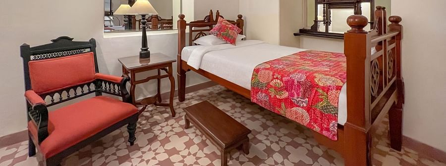 A room with a single bed, a chair, a small table, and a bench in Tijara Fort-Palace - 19th Century, Alwar.