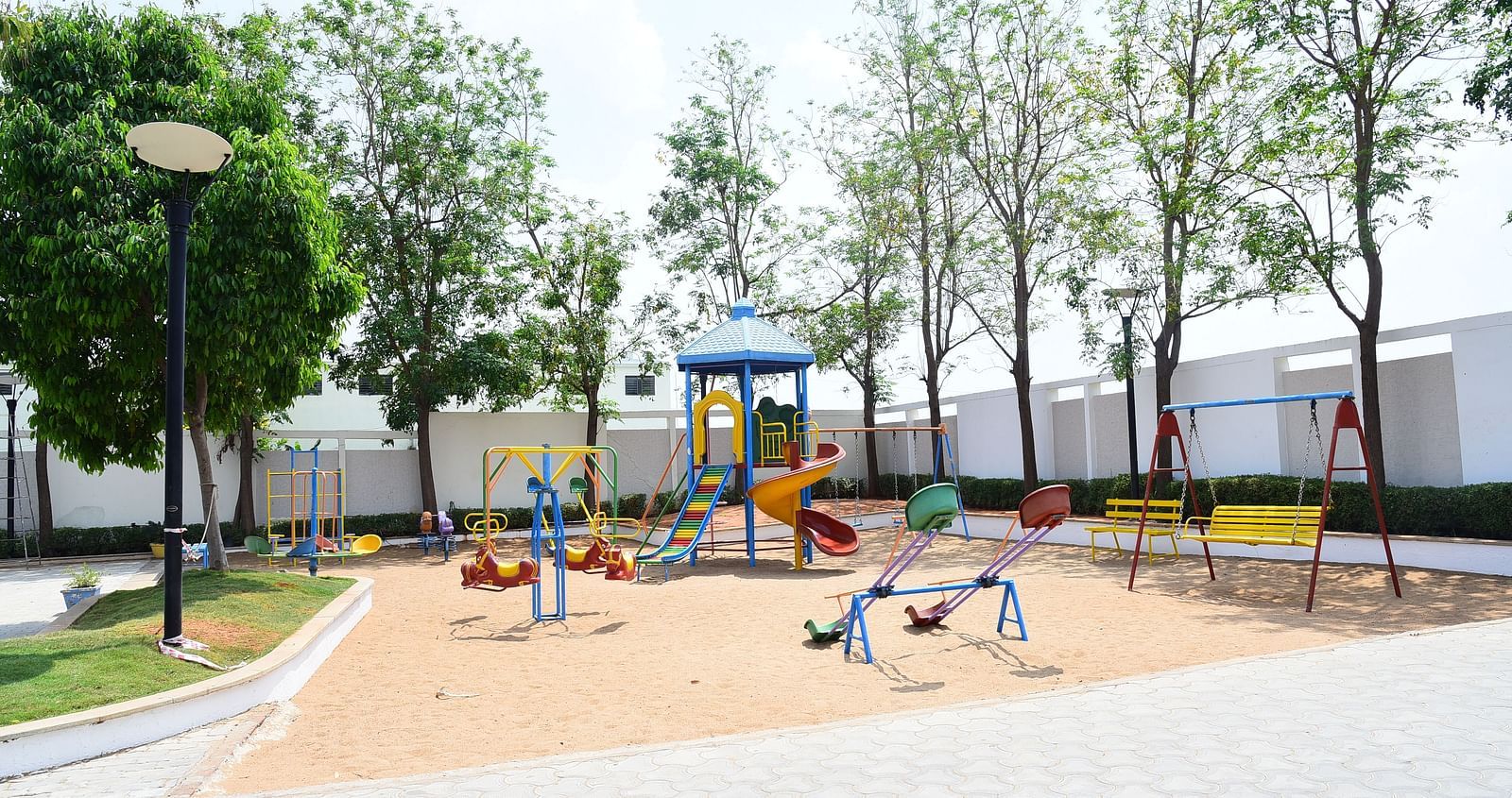 A well-maintained children's playground with swings and slides, providing a fun outdoor space.- Dhanalakshmi Srinivasan Hotels, Perambalur