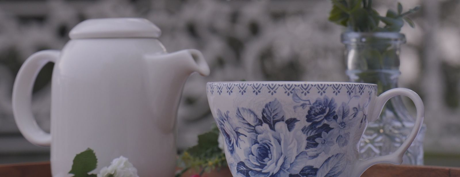 Outdoor tea setup with floral crockery and fresh pink flowers in soft focus - Mayfair Cafe & Suites, Dalhousie