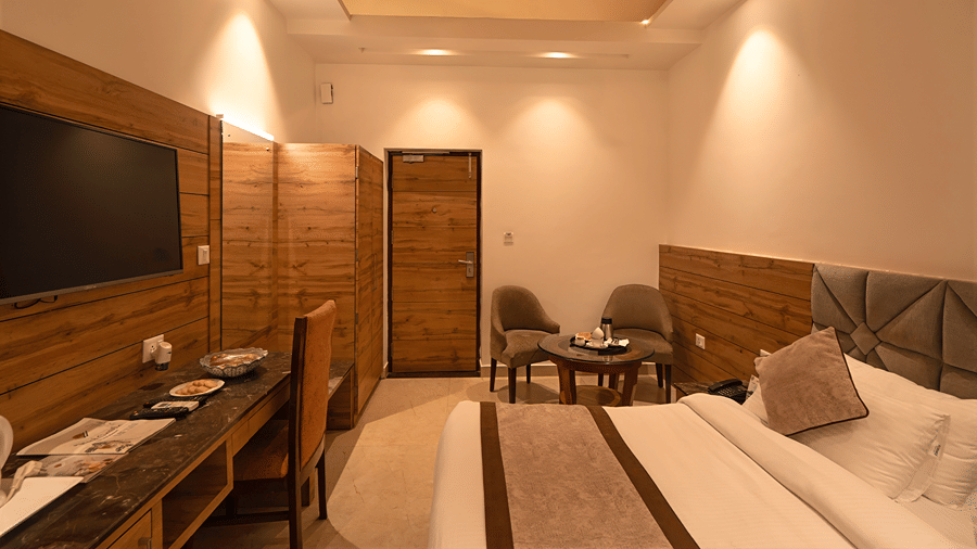 Elegantly lit resort room with warm recessed lighting, a comfortable double bed, work desk, and seating area - Wood Castle Spa & Resort, Jim Corbett