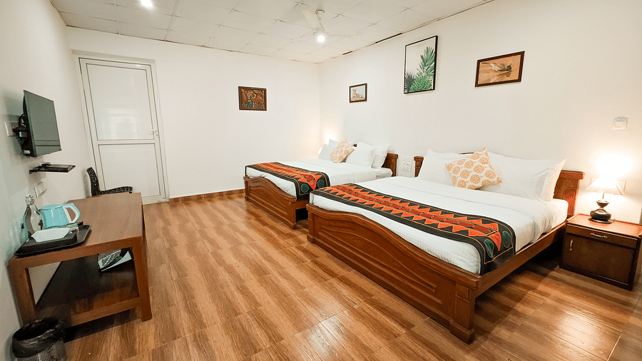 an overview of a bedroom with twin beds and lamps on each sides at Ibex Stays & Trails, Valparai (Mistly).