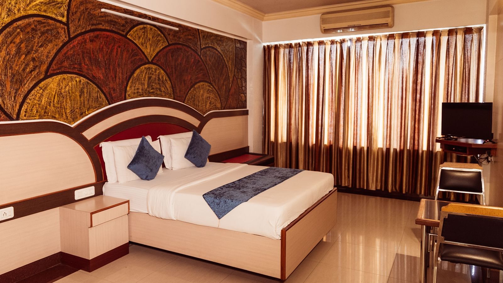 full view image of the executive room at the grand krishna room in bengaluru featuring a double bed and shiny curtains at the far end of the room
