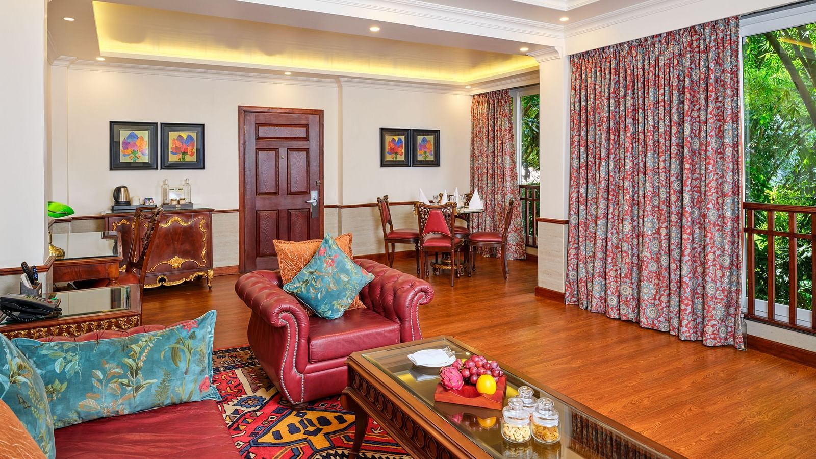 A room with sofas, table, cupboards, wall decor and curtained windows overlooking greenery at Mayfair Spa  Resort and Casino.