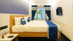 An image of a room with a bed, bed side table, and a window overlooking the view - MGM Whispering Nest