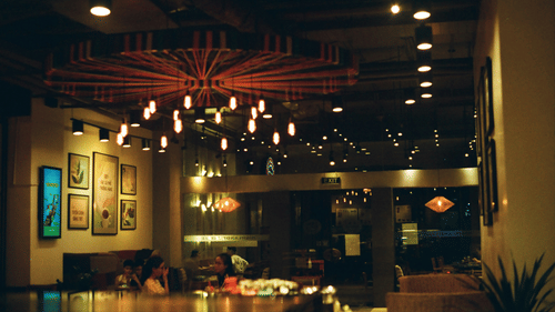 people sitting inside a cafe with dim lighting and art on the walls