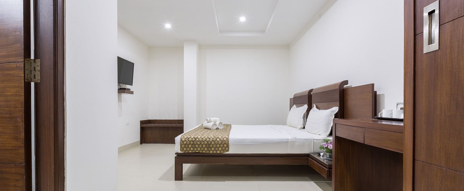 A room with a double bed and wooden furniture - Sanctum Suites BEL Road, Bangalore