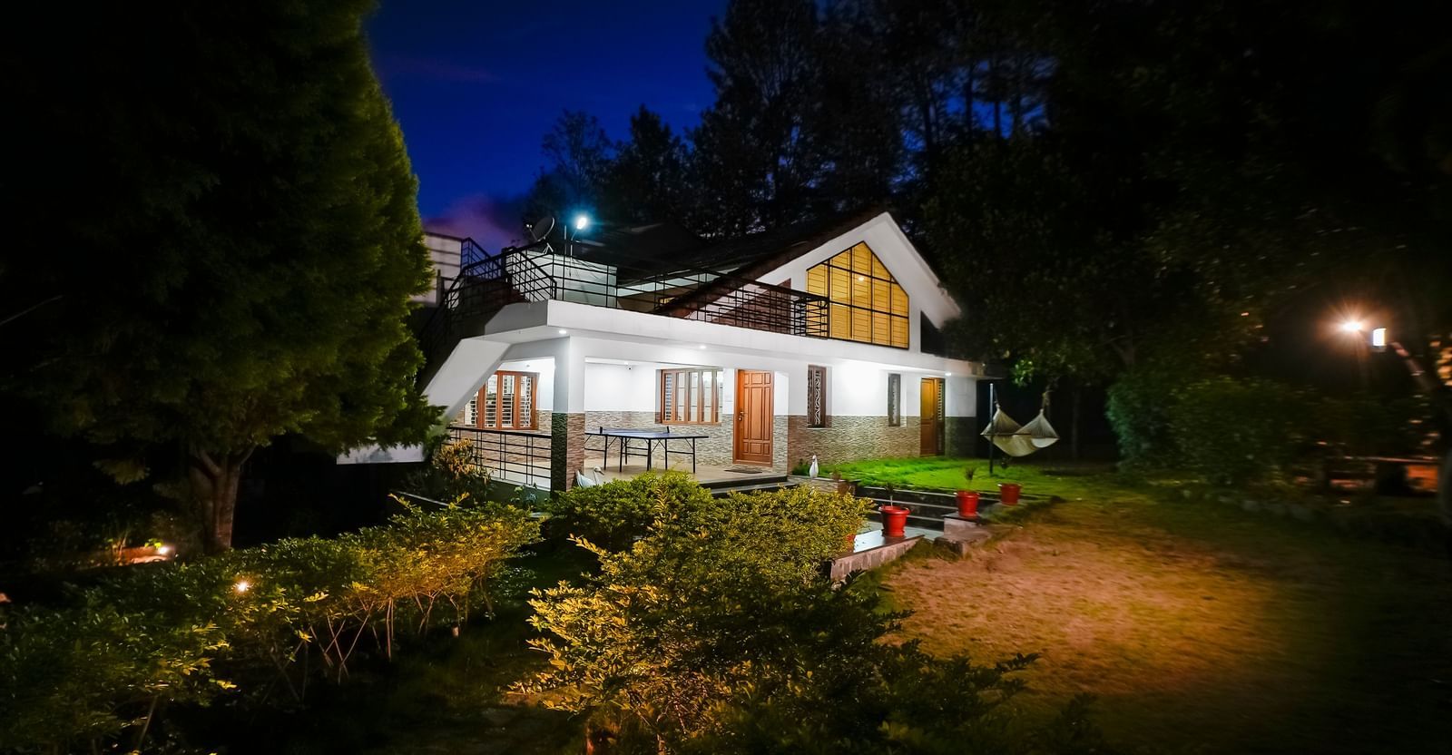 Facade view of WOW Bungalow, Yercaud, at night with a garden area.