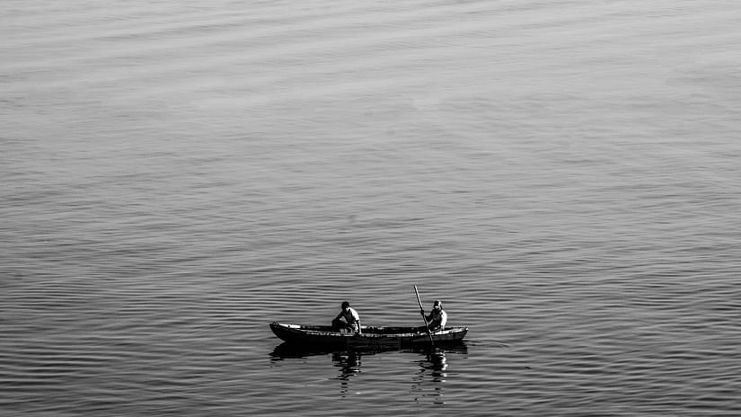 Black & white photo of the two people in a boat on a calm lake.
