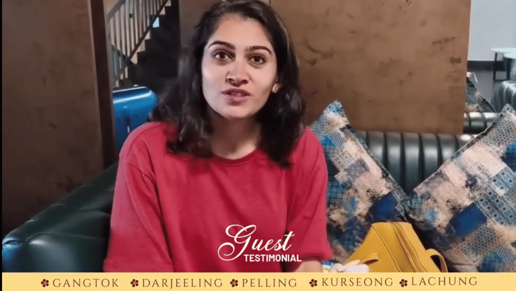 A female guest seated on a sofa at Avianna Group of Hotels & Resorts wearing a red sweatshirt and smiling while speaking. The hotel’s branding and contact information are displayed at the top and bottom of the image.
