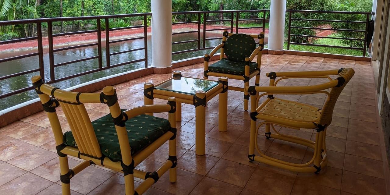 Outdoor seating area on a covered balcony with a scenic forest view at The Conservancy Bungalow.