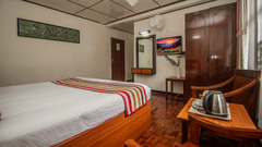 An image of bedroom featuring, a dressing table, TV, chair, table with a tea and coffee maker, and a fan - Central Hill Resort, Gangtok