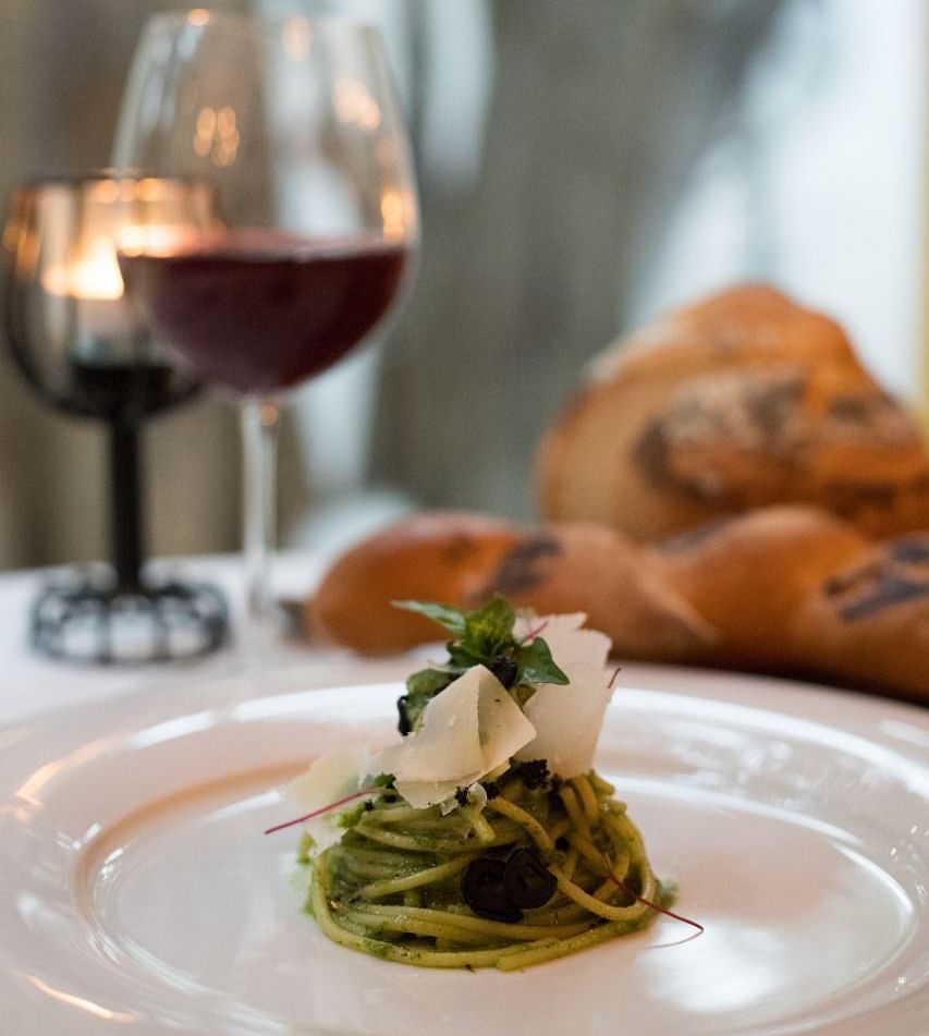image of pesto pasta served at the sevilla topped with fresh cheese - The Claridges New Delhi