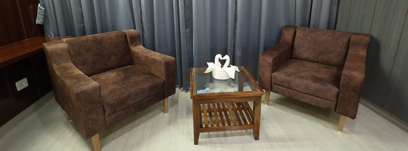 A small seating area in a room, featuring two brown plush armchairs and a small wooden table - Bamboo Saa Mulberry Resort, Pushkar