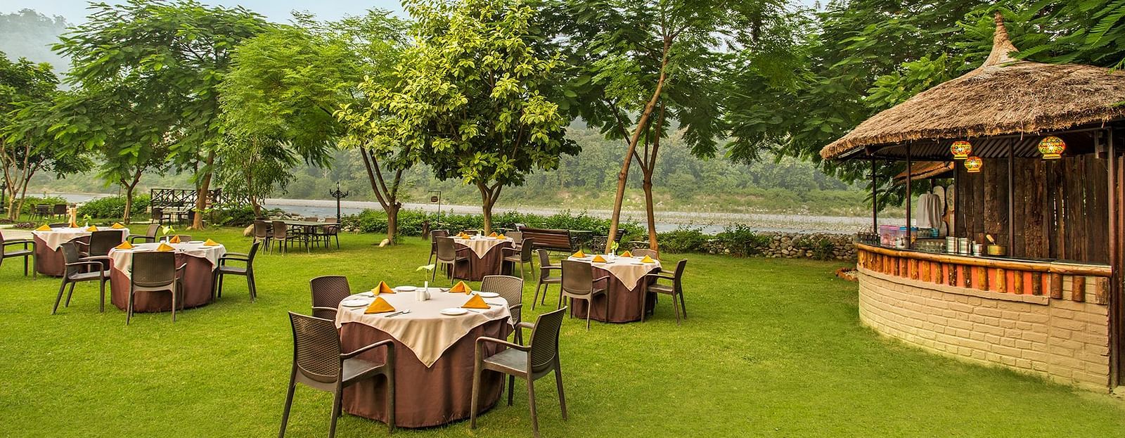 An image of a seating arrangement in a lawn near a hut - The Riverview Retreat,  Corbett