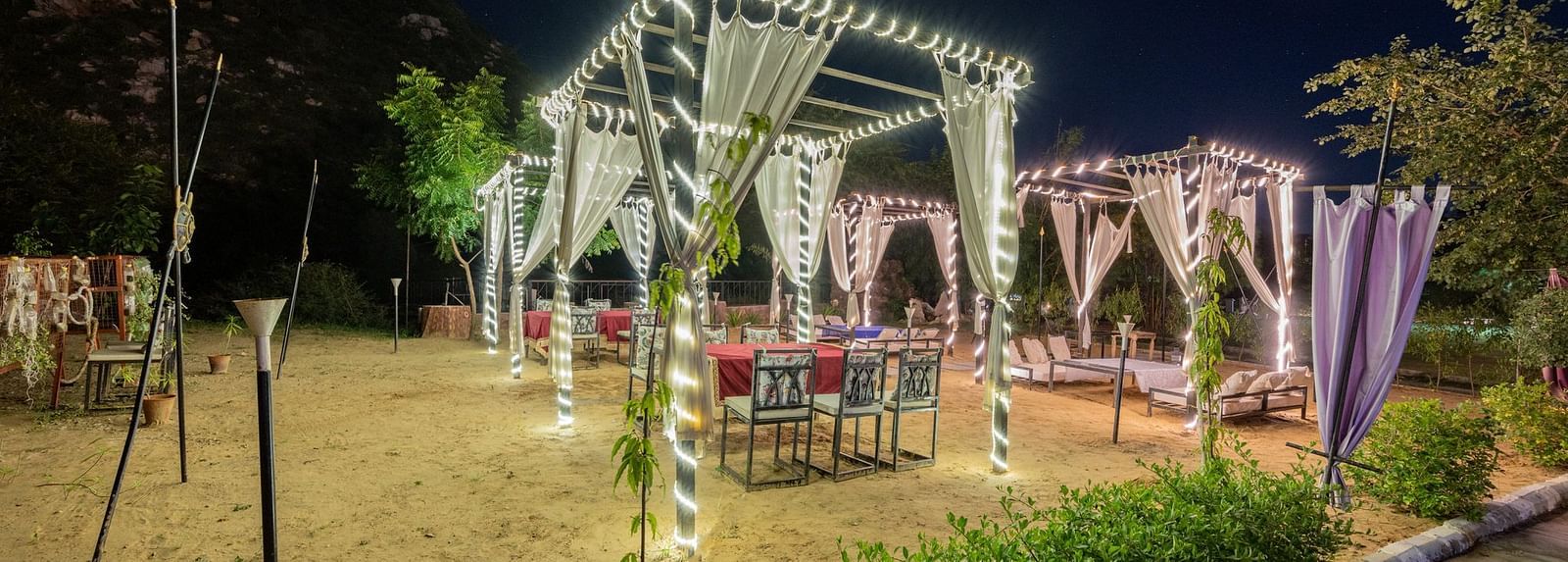 Night view of an open dining space decorated with sheer curtains and lights at Valley by Grassfield.