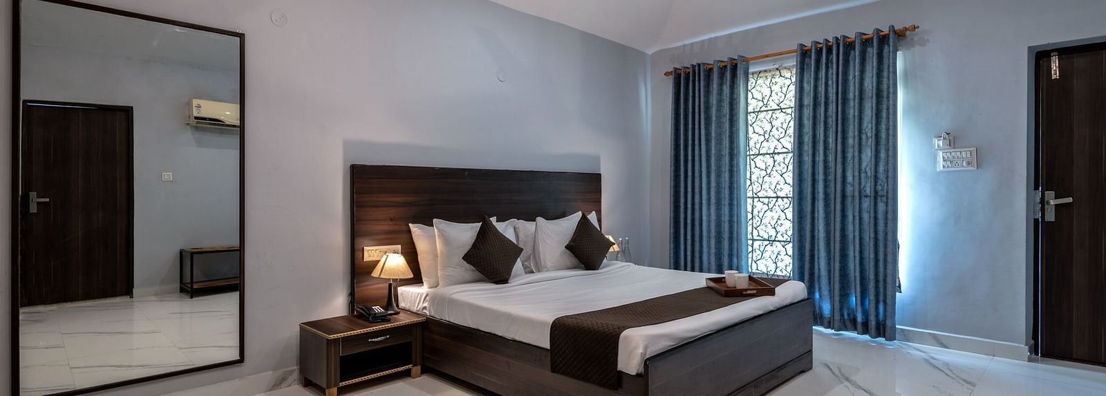 Side view of a room with a bed and a large mirror beside it at Valley by Grassfield.