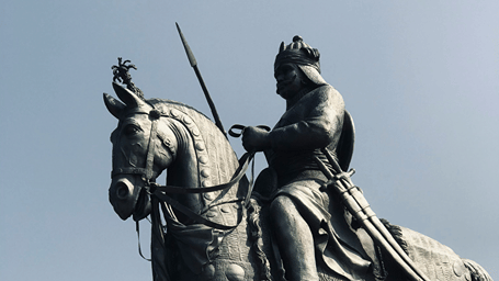 A grandeur statue of a rider on a rearing horse stands tall against a clear sky.