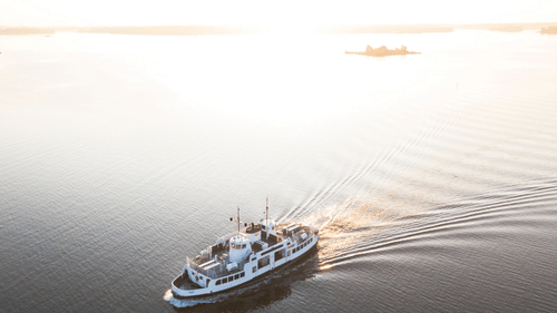 An aerial view of a ferry travelling on a water body while leaving waves behind - How to Reach Havelock Island