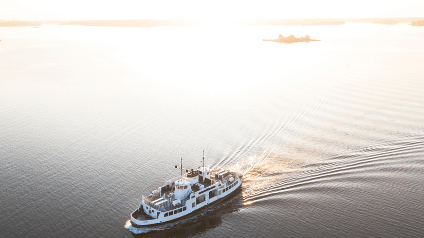 An aerial view of a ferry travelling on a water body while leaving waves behind - How to Reach Havelock Island