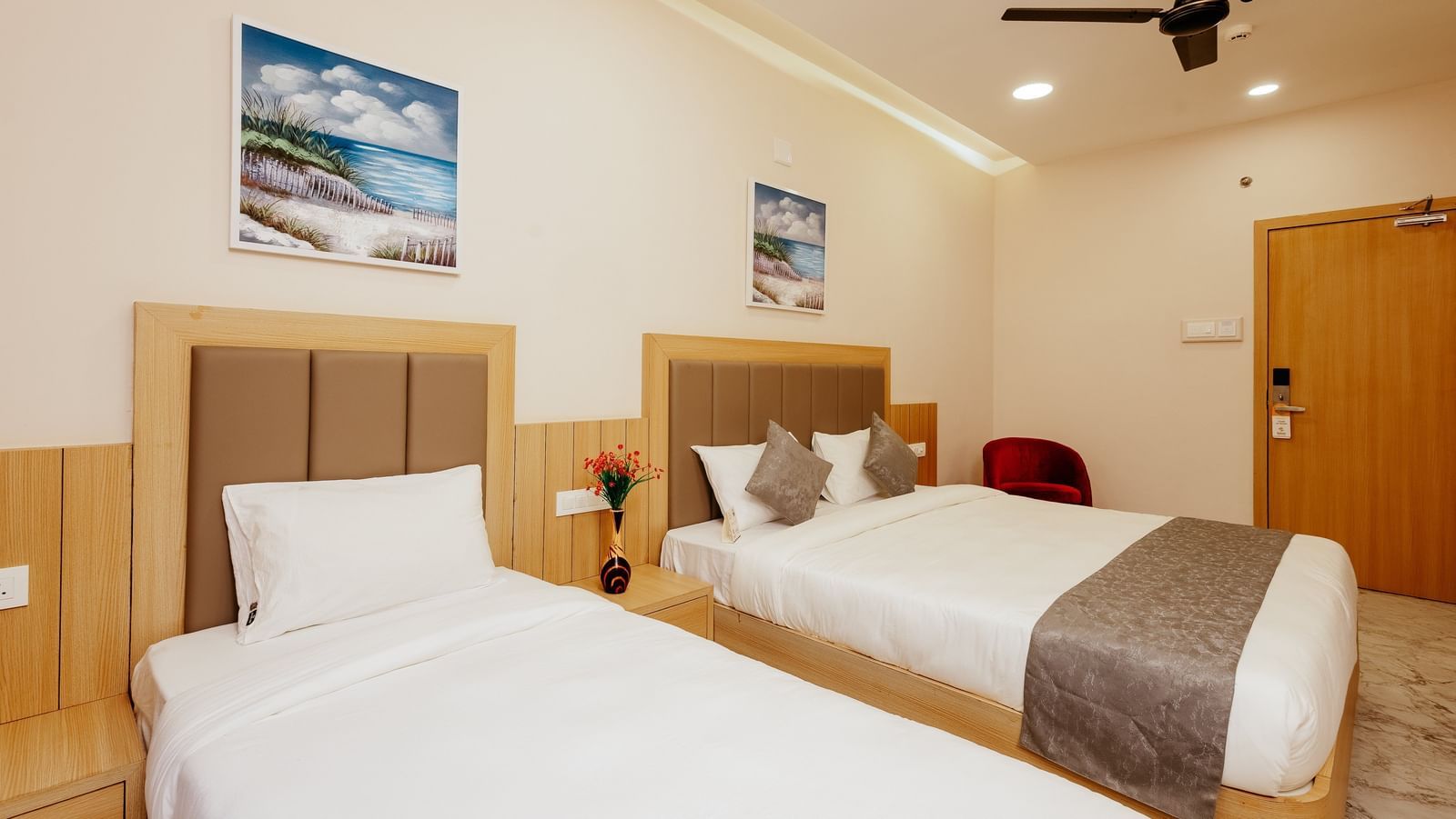 An inviting bedroom at Daksh The Grand Gowardhan, Dwarka, showcasing its clean linen, ample space, and art pieces hung above the bed.