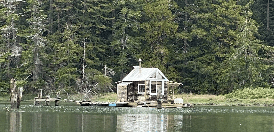 A house in the middle of a lake with mountains behind