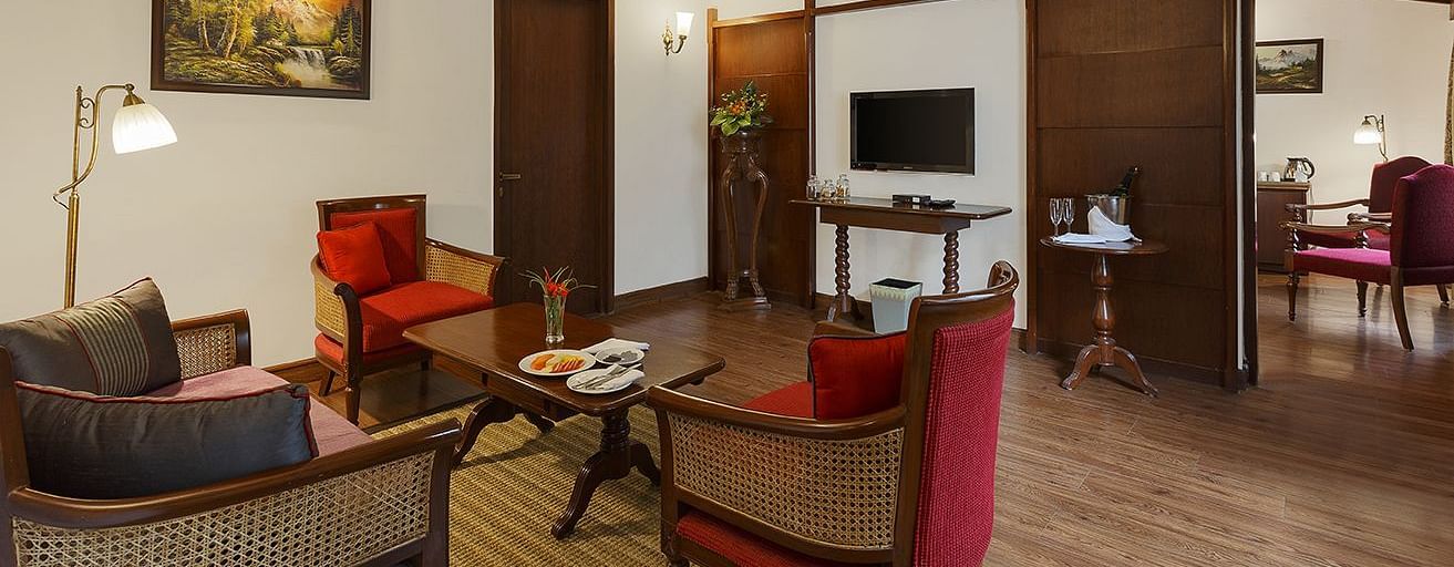 A spacious and luxurious living room with a comfortable seating arrangement, a coffee table, and a television. The room features a ceiling fan, wooden accents.