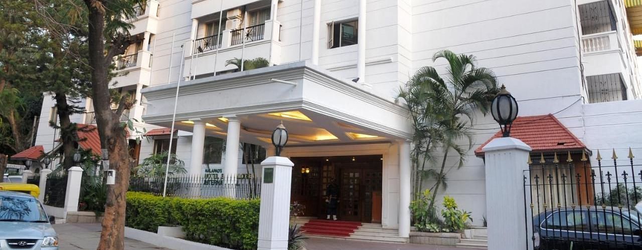 Nalapad Hotel Bangalore International, a white building with a covered entrance, landscaping, and parking.