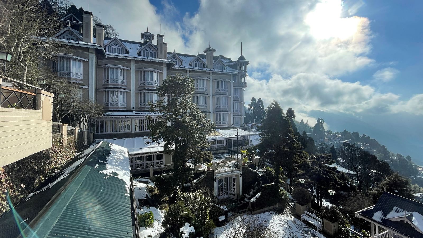 A misty morning view of Cedar Inn, Darjeeling, with clouds rolling over the hills and rooftops.