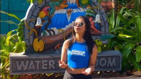Guest standing at a colorful water park entrance surrounded by greenery, highlighting slides, splashes, and a fun-filled experience.